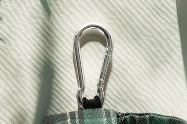 Gros plan sur le mousqueton de la pochette sac à crottes Nessie. Le design représente le tartan à carreaux vert écossais