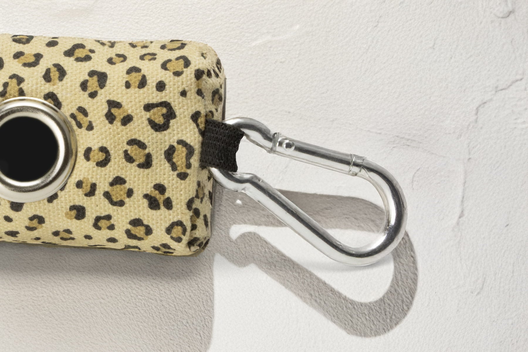 Gros plan sur le mousqueton de la pochette sacs à crottes Leopaw. Le motif de la pochette est en léopard. Le mousqueton permet une attache facile à une laisse ou autre support/accessoires