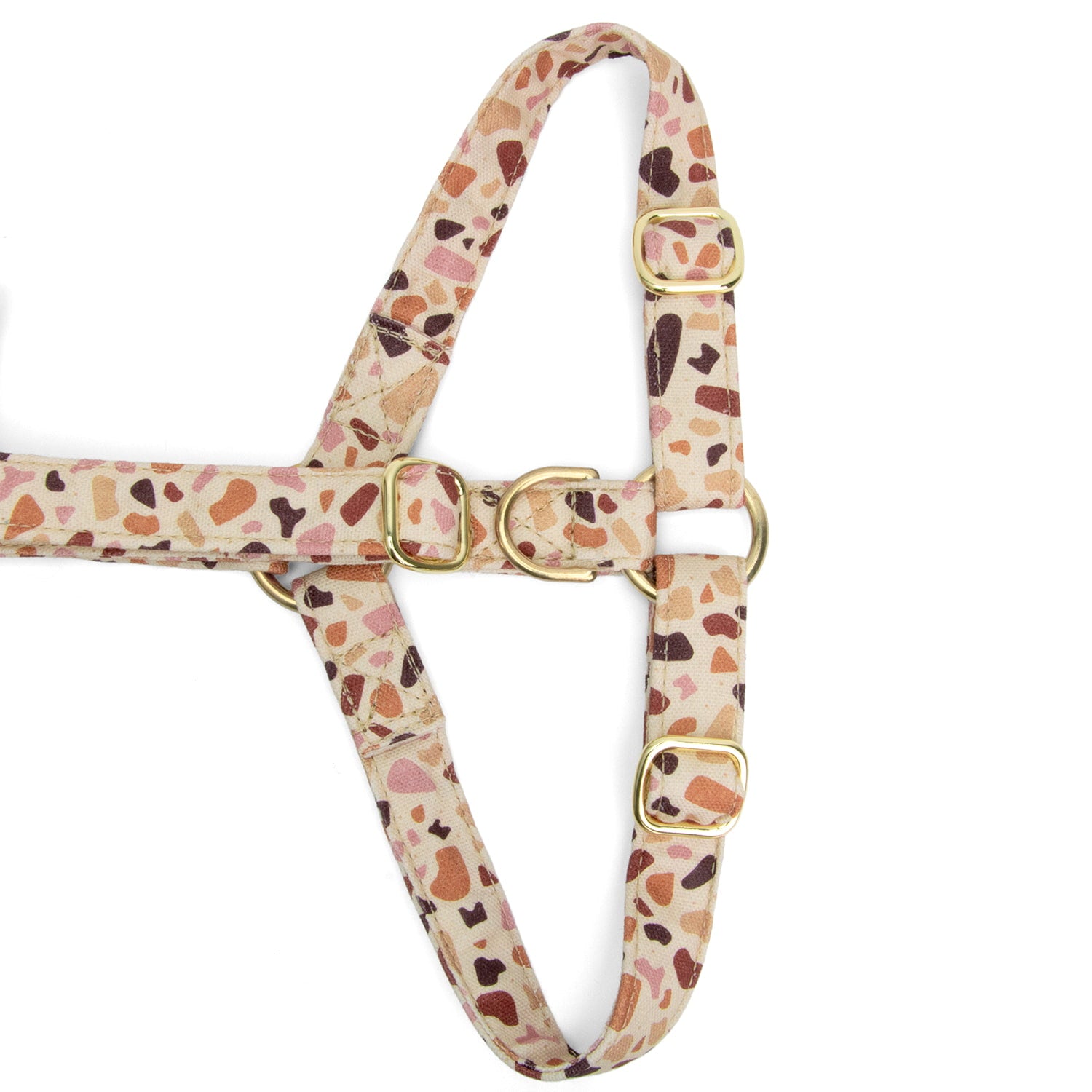 Gros plan de la boucle anti-traction du harnais en Y pour chien Pawpino et son motif terrazzo rose/marron. Les boucles sont couleurs or