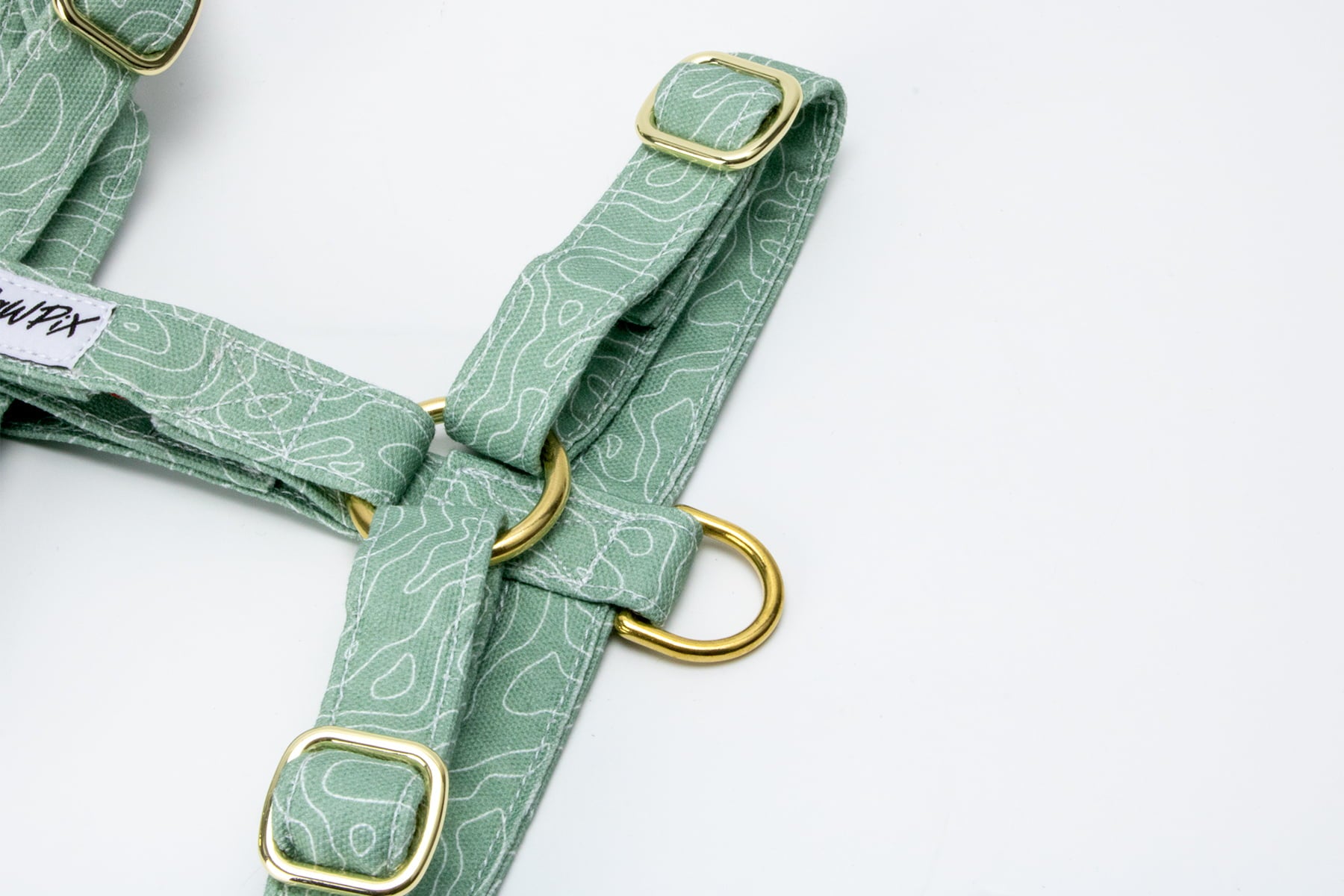 Gros plan sur la boucle anti-traction du harnais en H Topo. La boucle anti-traction sur un harnais en H redistribue la pression pour un meilleur contrôle et plus de confort lors des promenades.
 Le motif Topo reprend le design géométrique des cartes de montagnes, avec des lignes blanches sur un fond vert