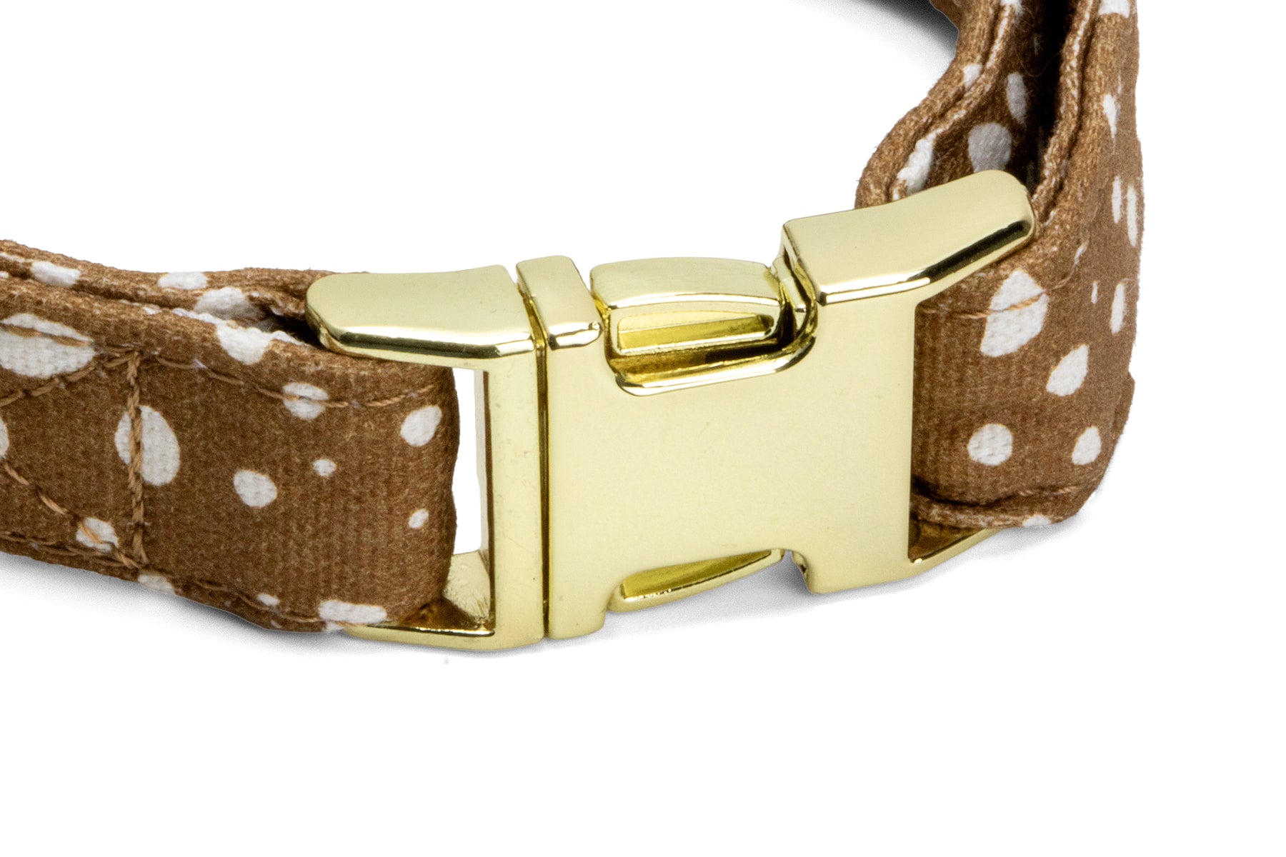 Gros plan sur la boucle du collier pour chien Freckles. Une boucle clips couleur or qui permet d'ouvrir et fermer le collier facilement. Le collier est motif marron tacheté blanc.