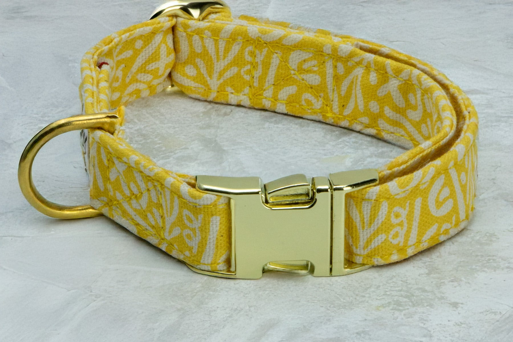 Gros plan sur les boucles du collier pour chien Seaside de Pawpix. Les boucles peuvent être de couleur or ou argentée. Le collier possède un motif marin abstrait blanc sur fond jaune solaire. Le collier pour chien possède une boucle  clips, un anneau en D pour attacher laisse et médaille et une boucle de réglage pour un ajustement parfait du collier 