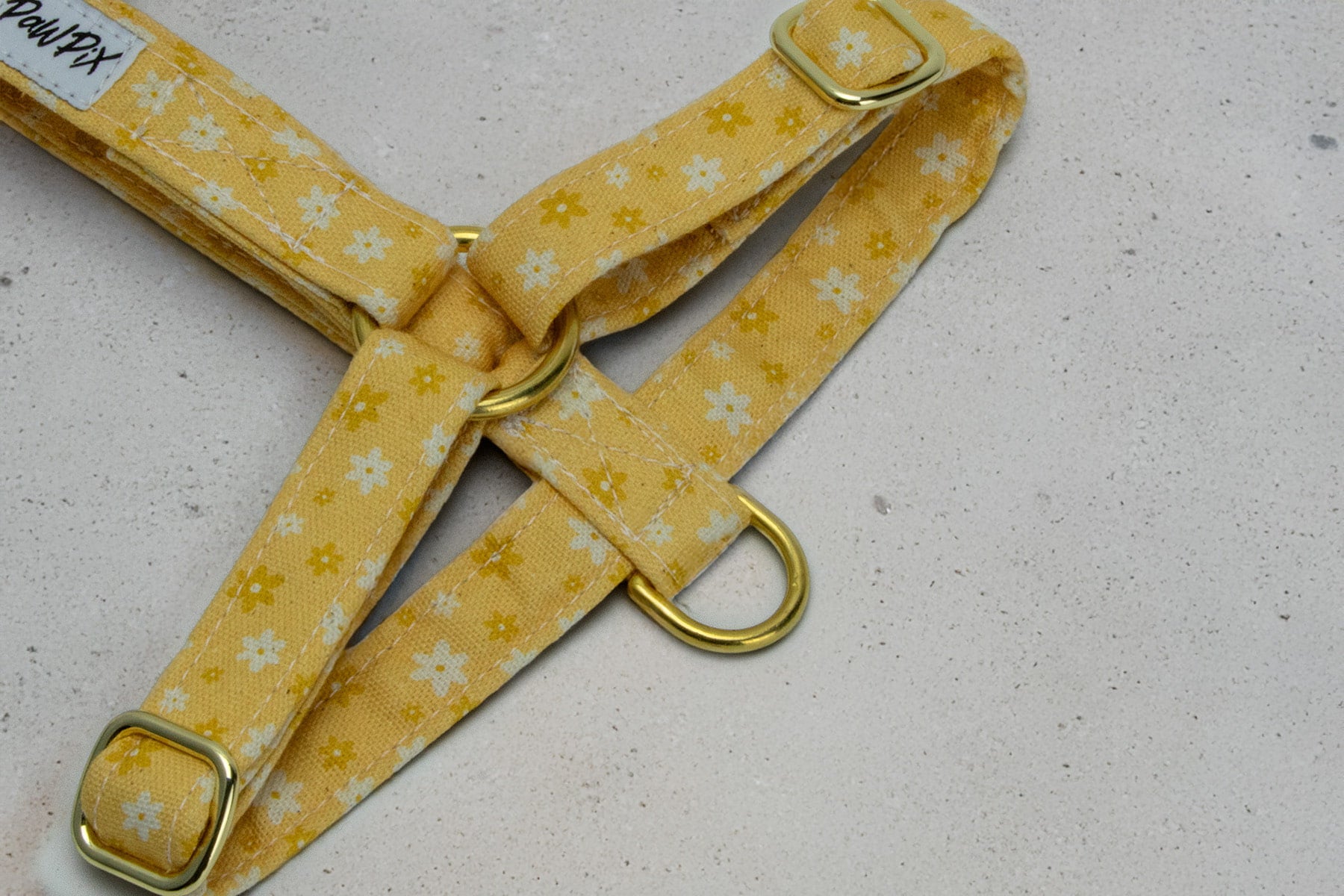 Focus sur les boucles de réglage et l'anneau anti-traction du harnais en H Peachy Daisies de Pawpix. Le harnais est au motif marguerites blanches et jaunes sur fond pêche 