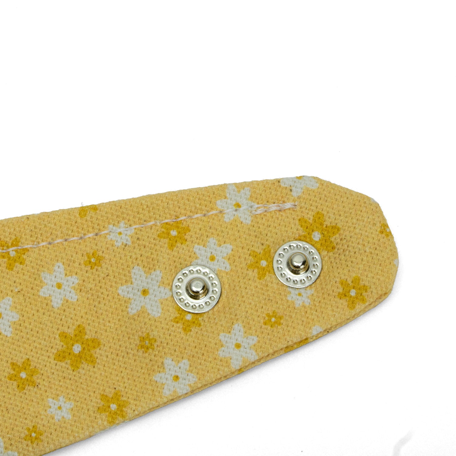 Gros plan des Boutons pression du bandana pour chien et chat Peachy Daisies de Pawpix et son motif marguerites blanches et jaunes sur fond couleur pêche. Les boutons pressions permettent de régler au mieux le bandana. 