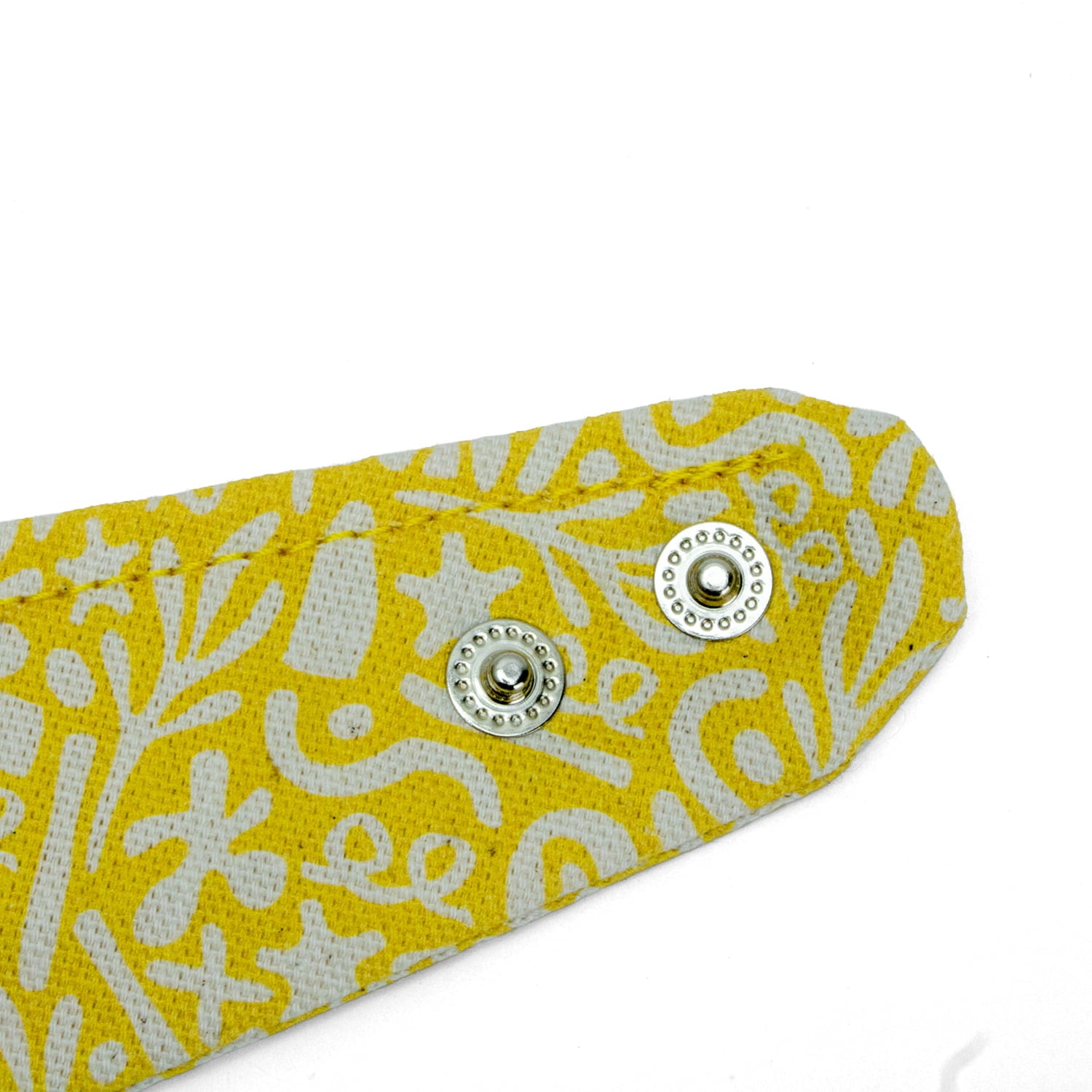 Gros plan des Boutons pression du bandana pour chien et chat Seaside de Pawpix et son motif marin abstrait blanc sur fond jaune. Les boutons pressions permettent de régler au mieux le bandana. 