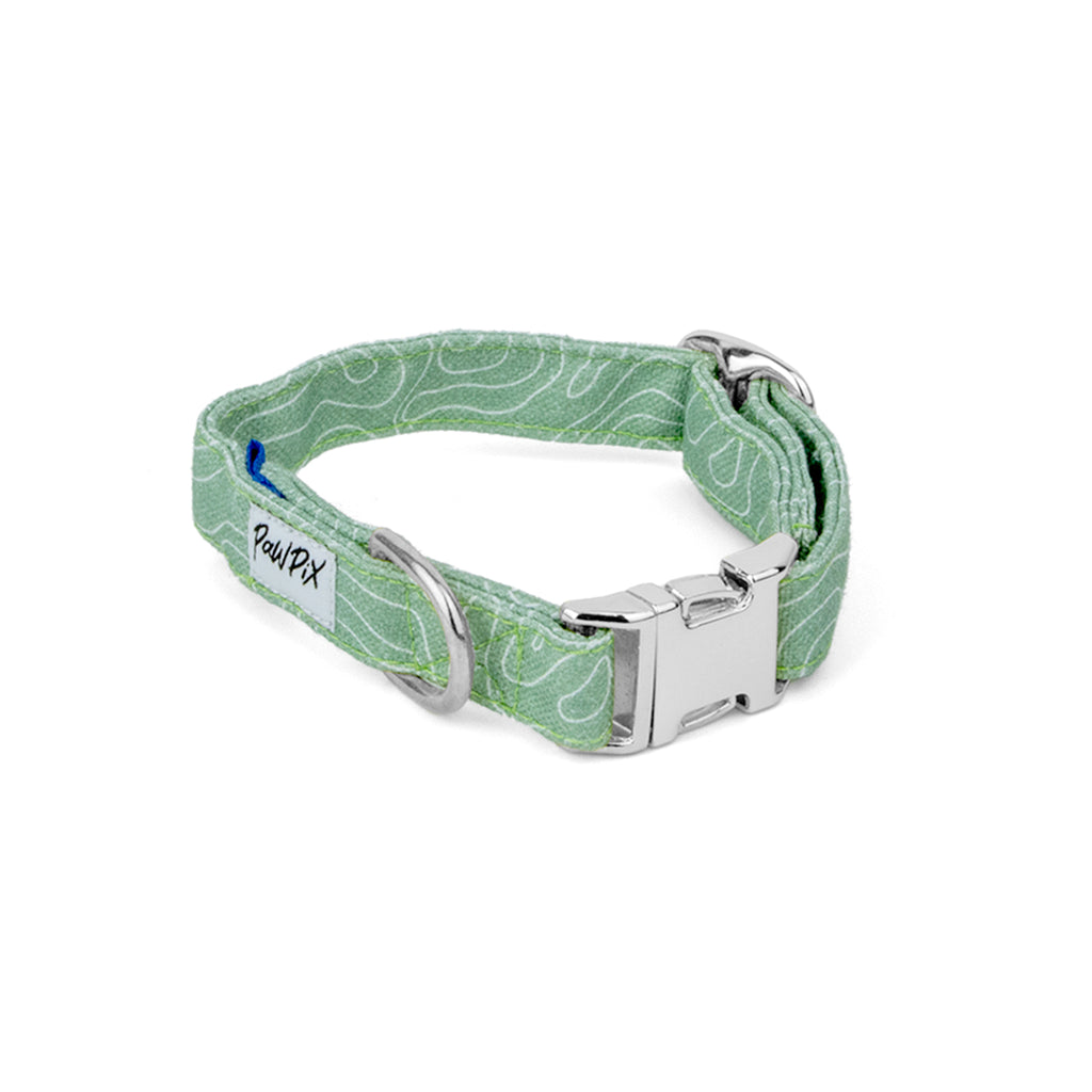 Collier pour chien Topo. Couleur vert clair avec un motif topographique, agrémenté d'une boucle clip, d'une boucle de réglage et d'un anneau couleur argent. Le motif Topo reprend le design géométrique abstrait des cartes de montagnes, avec des lignes blanches sur un fond vert