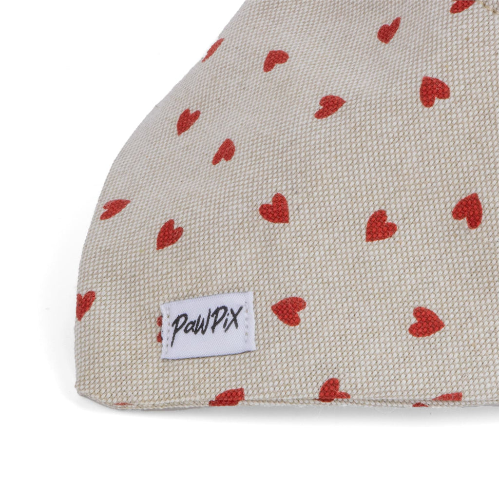 Gros plan sur le triangle du bandana My Valentine pour chien avec un motif cœur rouge sur un tissu couleur beige/marron. 