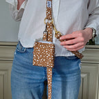 Plan serré de la mini sacoche Freckles pour chien portée sur une laisse multipostions du même motif tacheté blanc sur fond marron. 