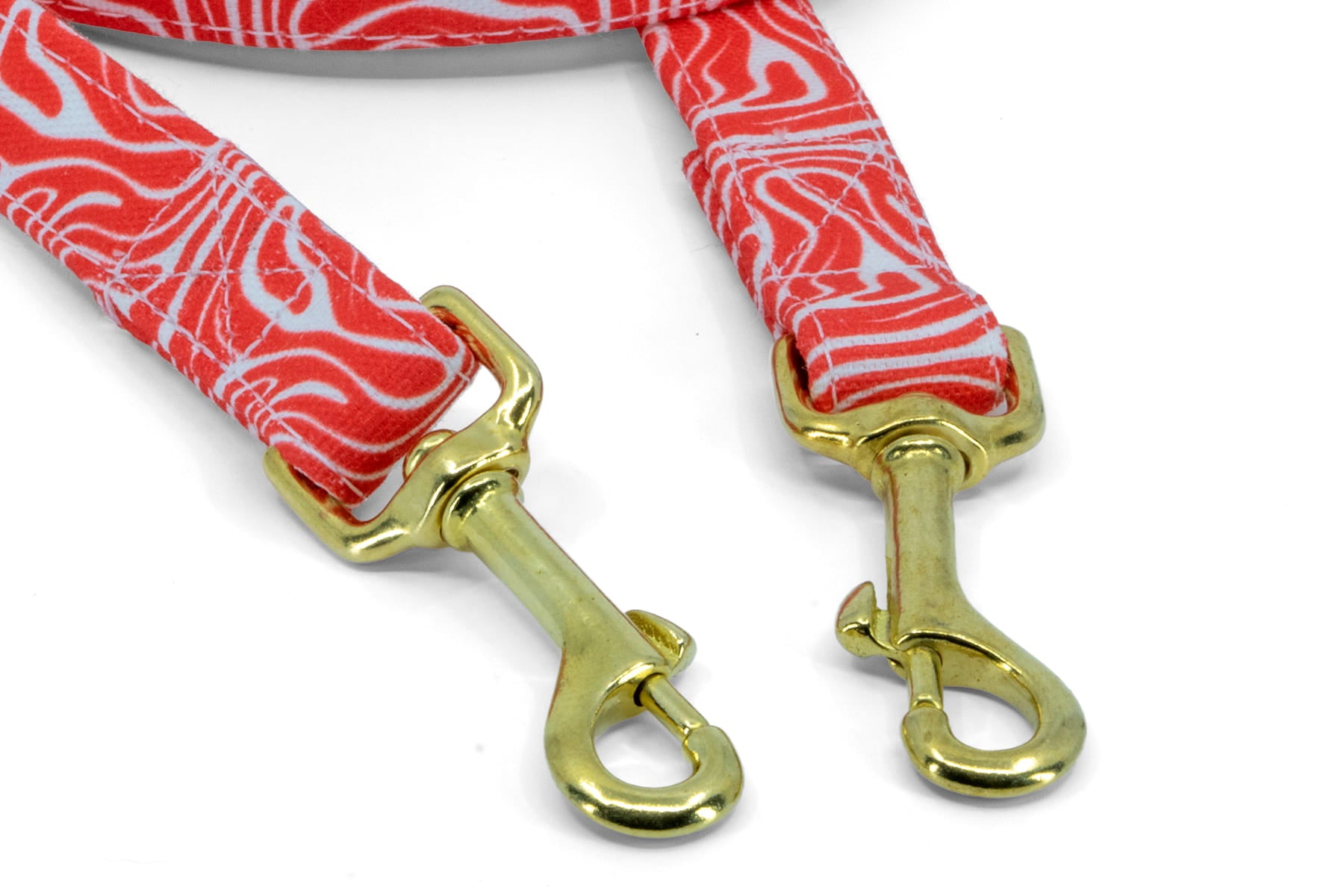 Gros plan des mousquetons de la laisse multipositions pour chien Cherry de Pawpix. Motif rouge et blanc wavy et mousqueton couleur or/laiton. 