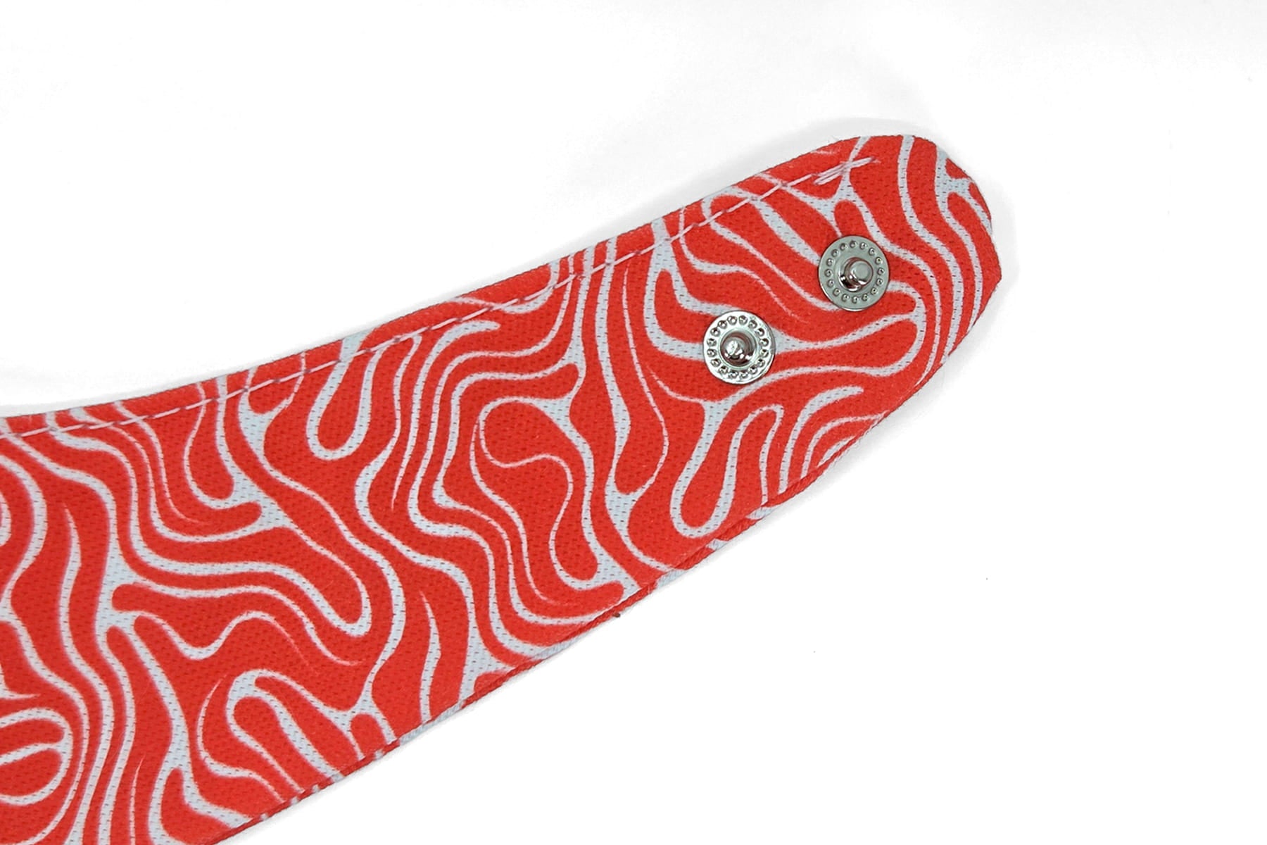 Gros plan des boutons pressions du bandana pour chien et chat Cherry de Pawpix. Motif rouge et blanc wavy