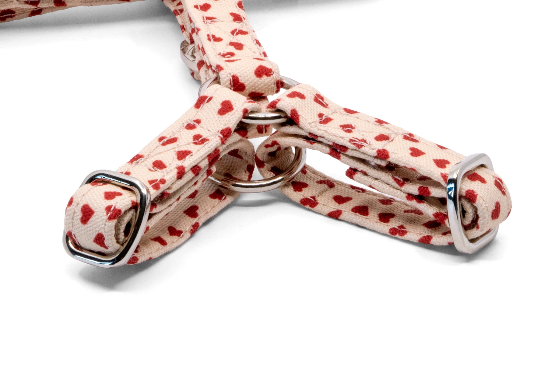 Gros plan sur la forme en Y du harnais pour chat My Valentine de Pawpix et son motif cœurs rouges sur fond beige