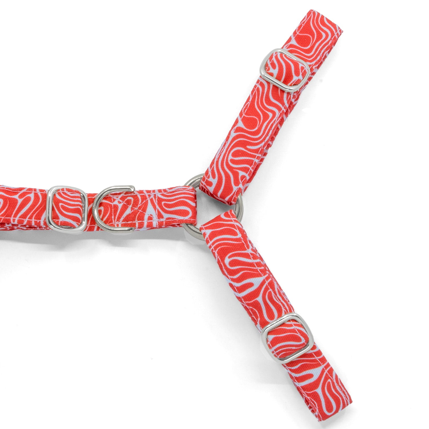Plan rapproché de la boucle anti-traction du harnais en Y Cherry de Pawpix. La boucle est présente sur la partie poitrail du harnais et de couleur argent. Le harnais présente un motif rouge et blanc wavy