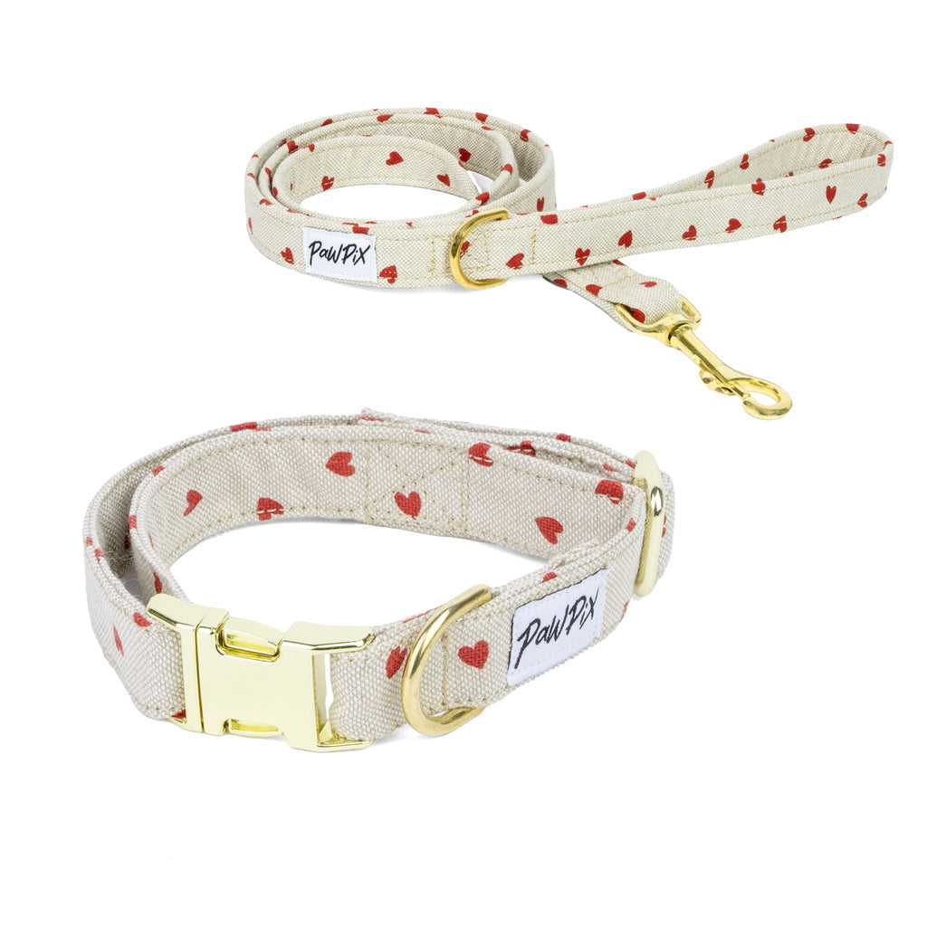 Kit de balade pour chien My Valentine. Le kit comprends une laisse et un collier au design My Valentine à savoir des cœurs rouges sur un fond beige clair. Les boucles sont de couleurs or clair.