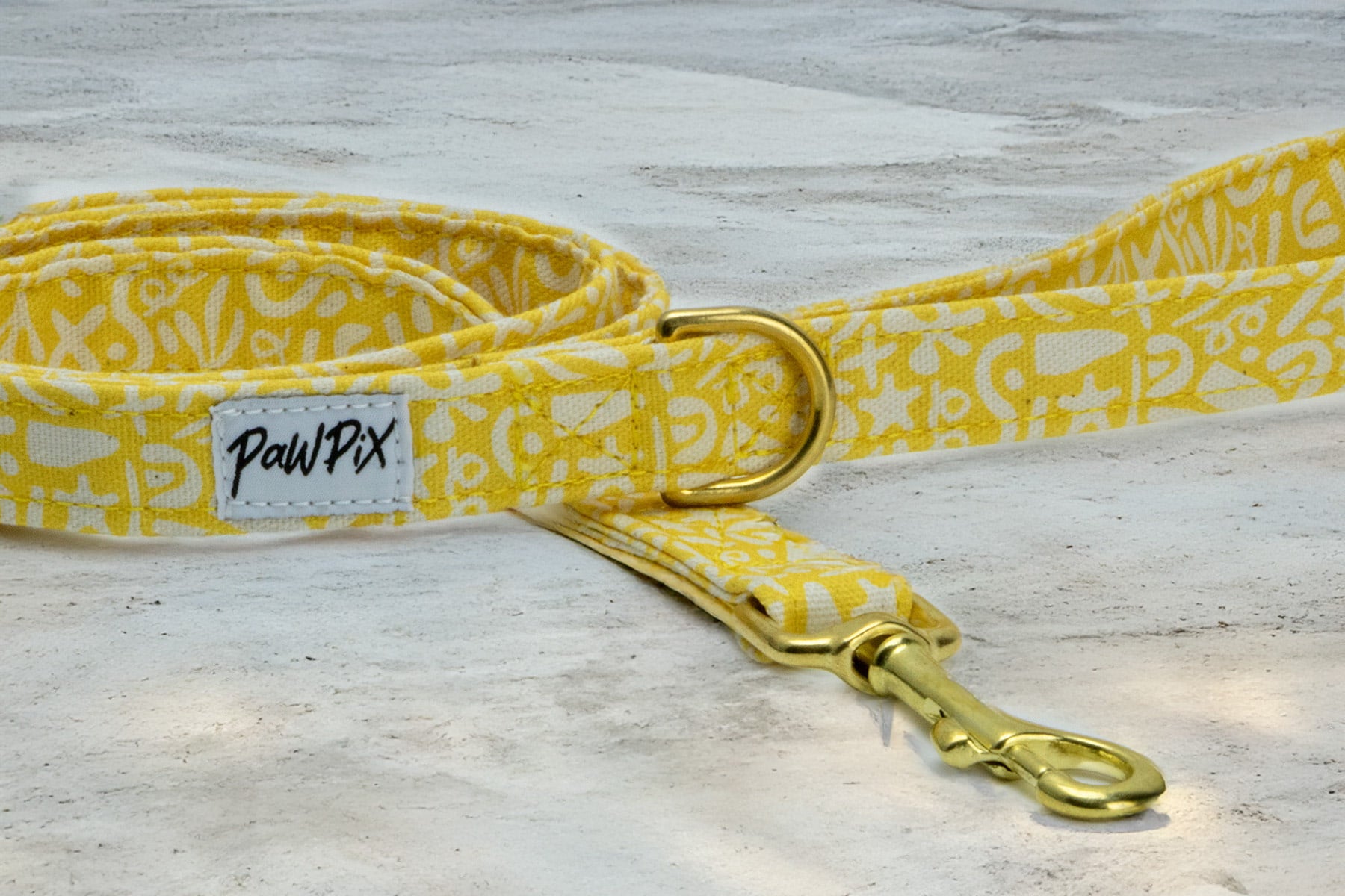 Focus sur la boucle en D et le mousqueton de la laisse pour chien Seaside. La laisse est avec un motif marin abstrait blanc sur un fond jaune solaire