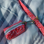 Vue rapprochée de la pochette sacs à crottes Cherry de Pawpix accrochée à la laisse Cherry de Pawpix. Les deux produits présentes un motif rouge et blanc wavy. 