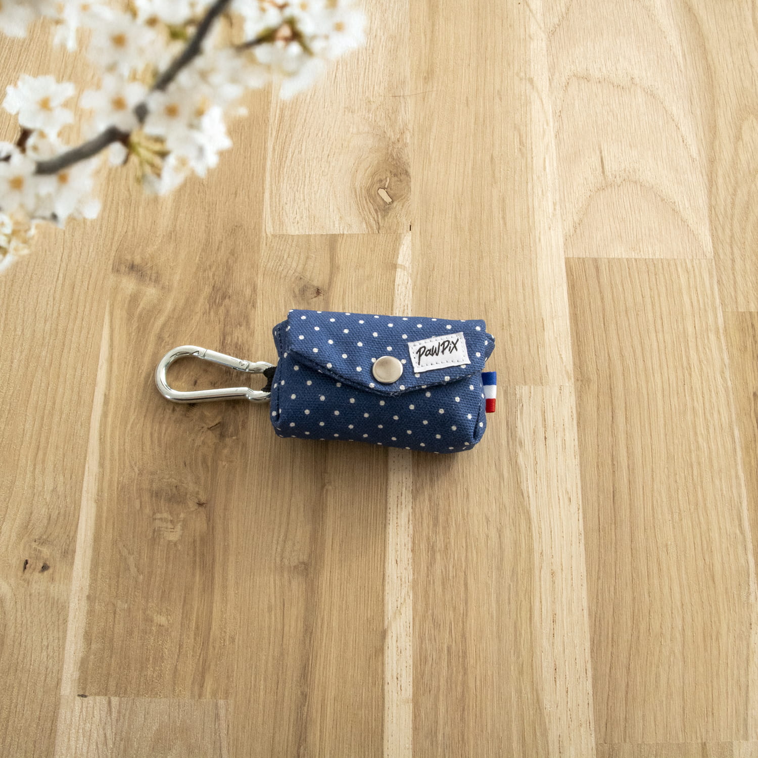 Pochette pour sac à crottes Polaris. Design bleu marine avec des pois blancs. La pochette comporte un mousqueton et un œillet pour pouvoir avoir accès facilement aux sacs 