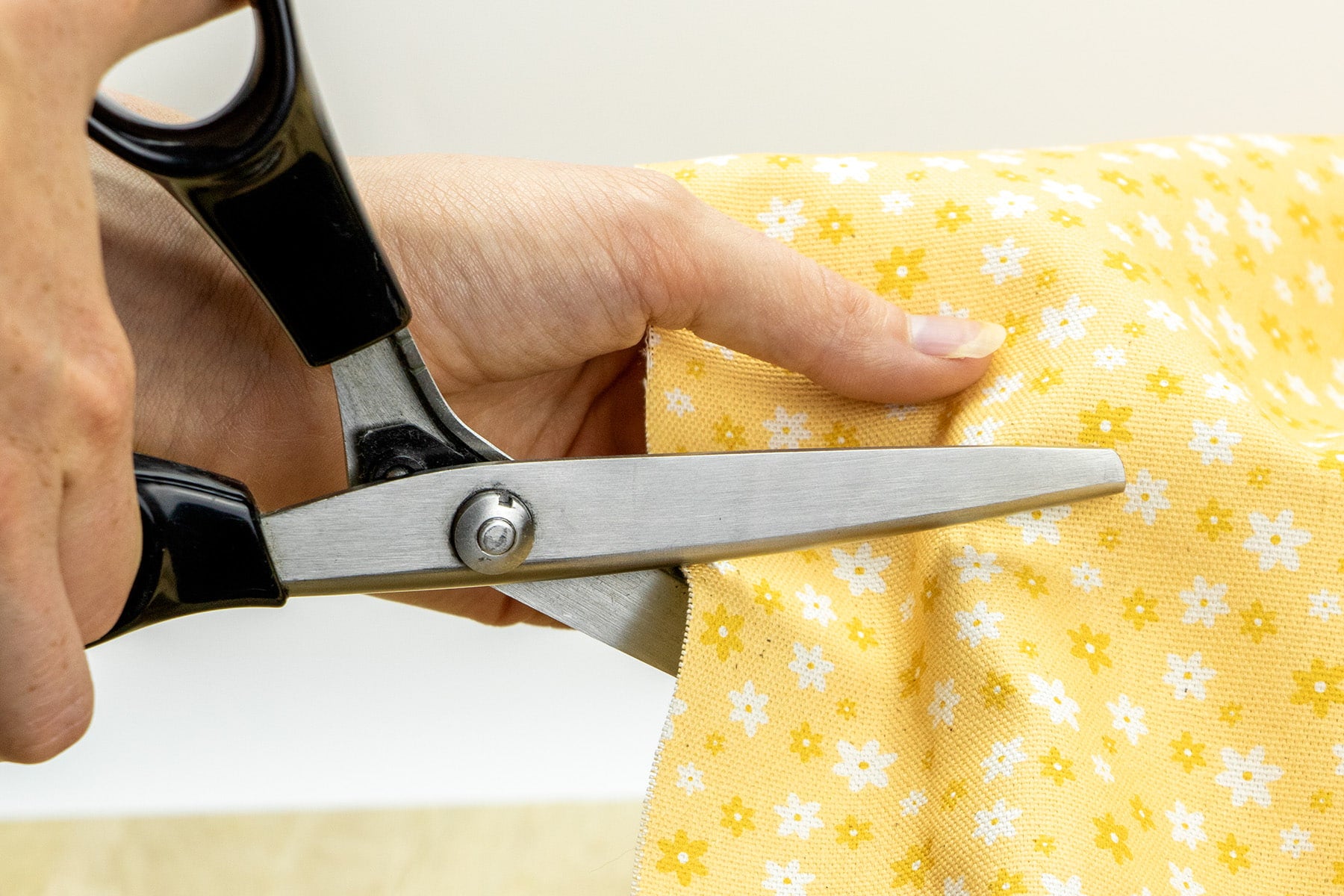 Coupe du tissu Peachy Daisies avec ses marguerites blanches et jaunes sur fond couleur pêche. Le tissu est utilisé pour les accessoires Pawpix comme les colliers pour chien et chat, les harnais, les bandanas, laisses et pochettes sacs à crottes