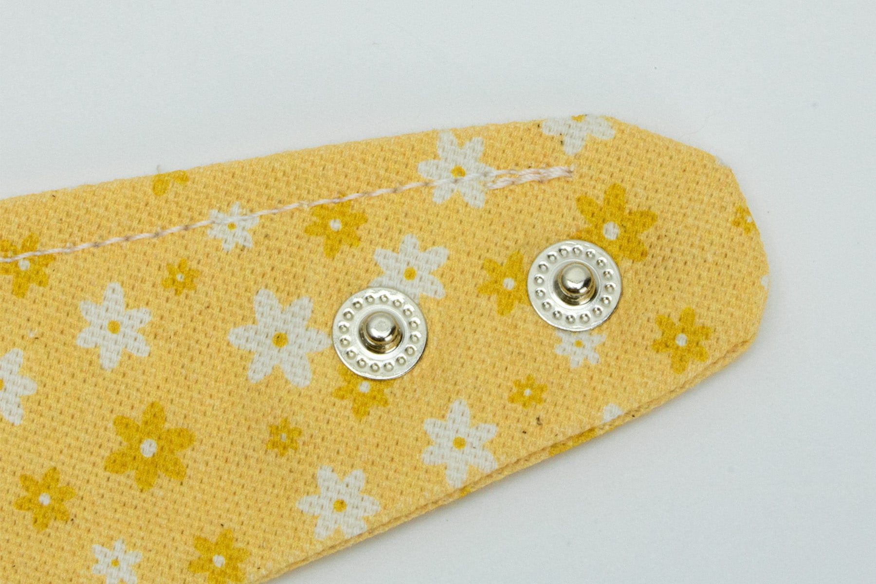 Gros plan sur les boutons pression du bandana pour chien et chat Peachy Daisies. Les boutons pressions permettent un meilleur ajustement du bandana 